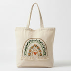 Beige tote bag with embroidered rainbow design on a white background