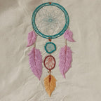 Embroidered dreamcatcher with feathers on a beige fabric background