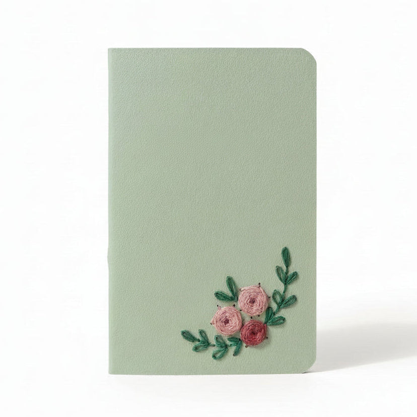 Light green notebook with floral embroidery on a white background