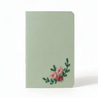 Light green notebook with floral embroidery on a white background