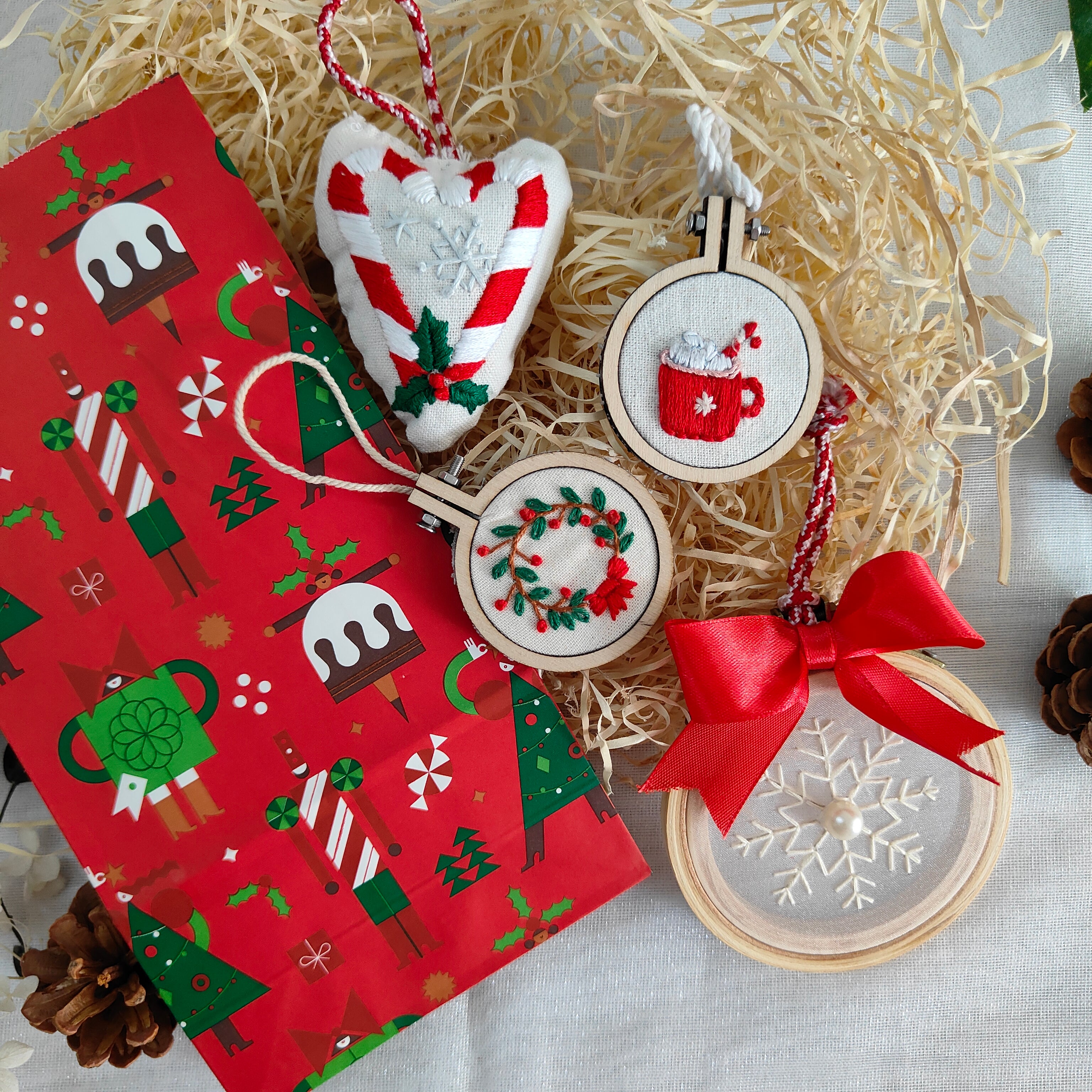 Decorative Christmas ornaments with a red patterned box on a light background